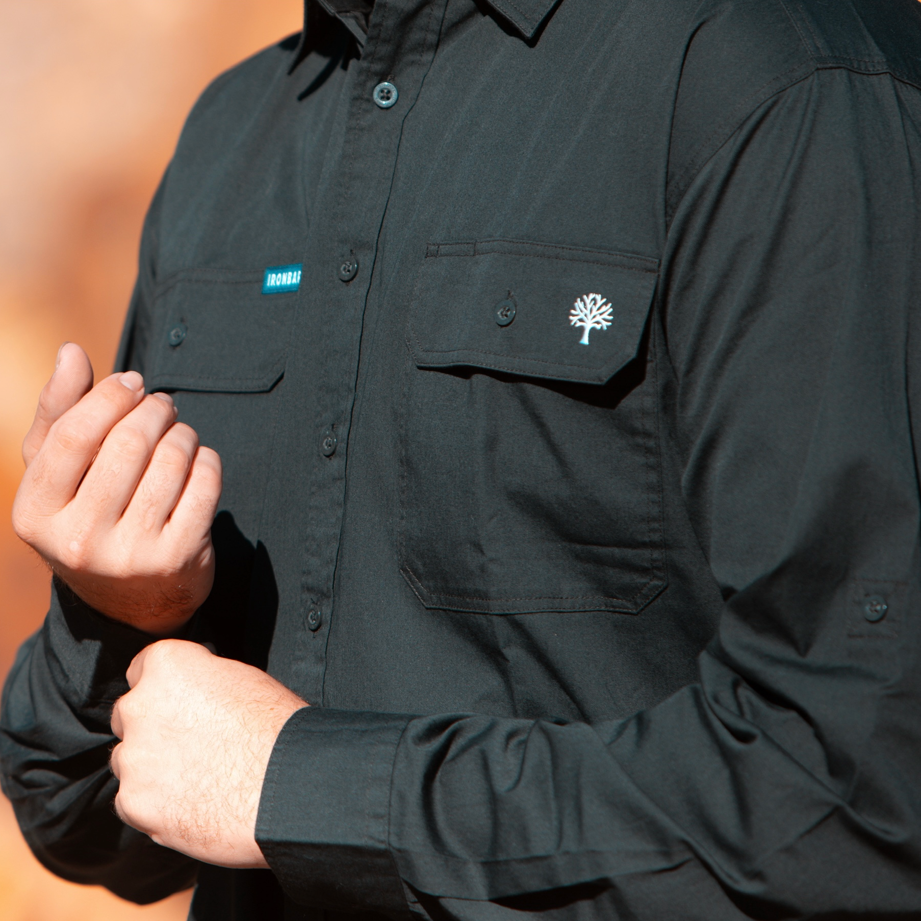 Black shirt with logos on chest and sleeve against a blurred background